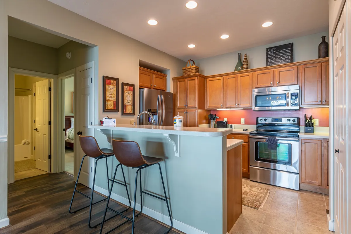 A view of the kitchen with a spacious island, stainless steel appliances, and wooden cabinetry. The design is open and welcoming, with enough room for multiple guests to cook or socialize.