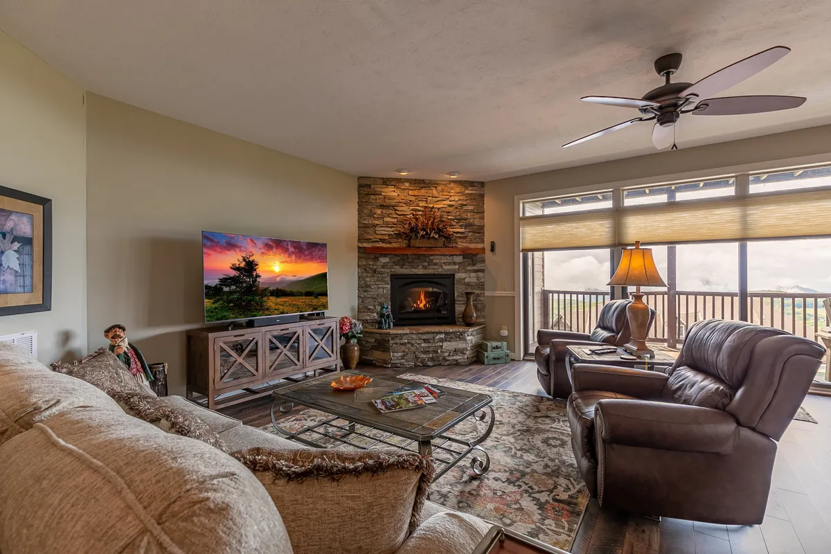 The image captures a welcoming living area featuring a gas fireplace, a large TV, and plush seating arranged around a coffee table. Sunset light filters in through the window, offering a glimpse of the outdoors and creating a cozy post-adventure atmosphere.