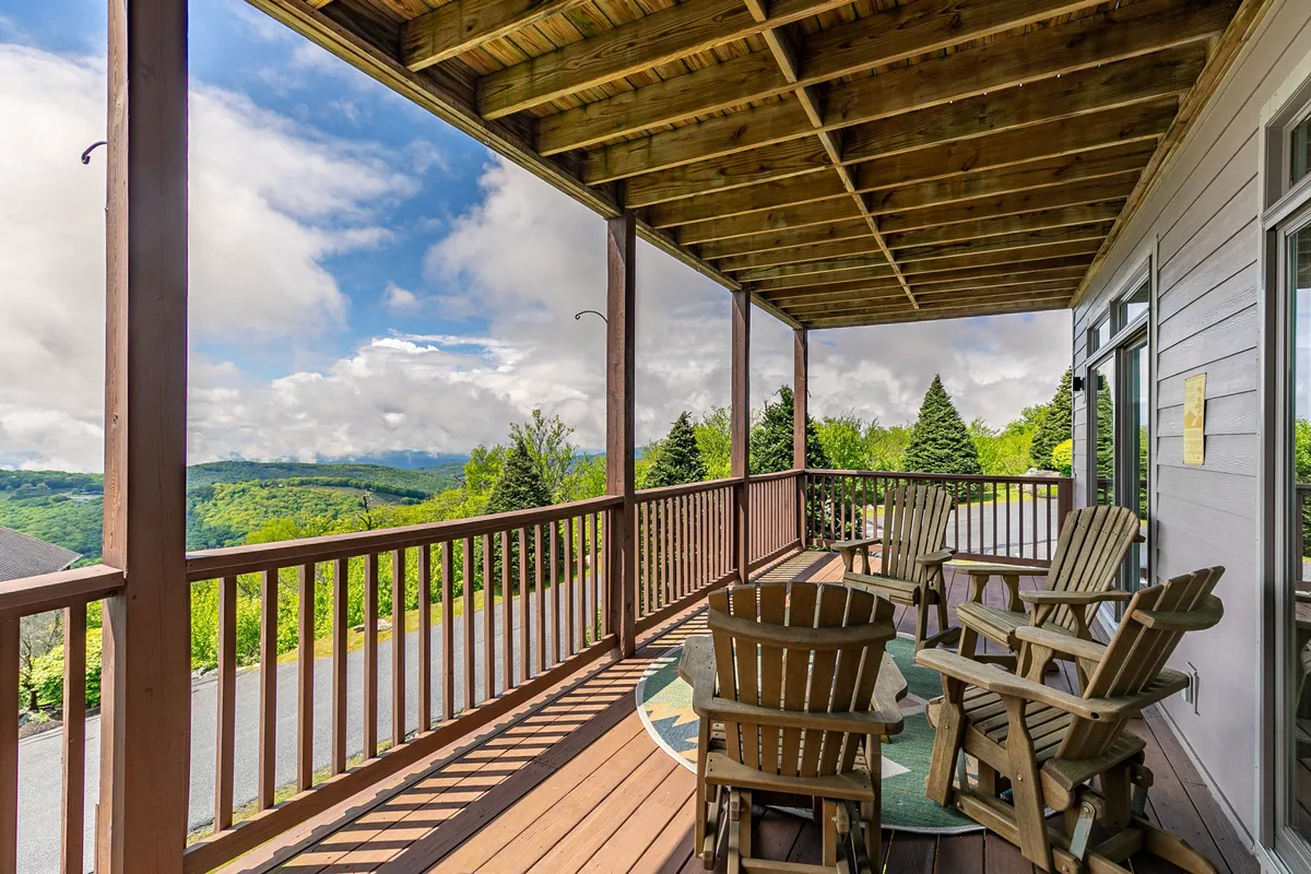 A private wooden deck furnished with rocking chairs and offering panoramic views of the surrounding mountains. The outdoor space feels tranquil and inviting, extending directly from the living area.